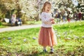 Adorable little girl enjoying nice and sunny spring day near apple tree in full bloom Royalty Free Stock Photo