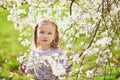 Adorable little girl enjoying nice and sunny spring day near apple tree in full bloom Royalty Free Stock Photo