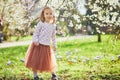 Adorable little girl enjoying nice and sunny spring day near apple tree in full bloom Royalty Free Stock Photo