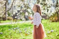 Adorable little girl enjoying nice and sunny spring day near apple tree in full bloom Royalty Free Stock Photo