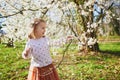 Adorable little girl enjoying nice and sunny spring day near apple tree in full bloom Royalty Free Stock Photo