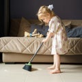 Cute little girl sweeping floor with broom at home