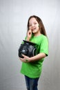 Adorable little girl in green T-shirt with clover leaf on her cheek taste gold cont and holds cast iron pot with leprechaun Royalty Free Stock Photo