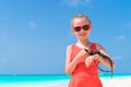 Adorable little girl happily holds a wild tropical lizard on white tropical beach