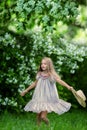 Adorable little girl in a hat in a blooming apple tree garden on a beautiful spring day. Cute child picking fresh apple tree Royalty Free Stock Photo