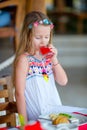 Adorable little girl having breakfast at outdoor cafe. Lid drinling fresh juice Royalty Free Stock Photo