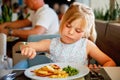 Adorable little girl having breakfast at resort restaurant. Happy preschool child eating healthy food, vegetables and Royalty Free Stock Photo