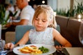 Adorable little girl having breakfast at resort restaurant. Happy preschool child eating healthy food, vegetables and Royalty Free Stock Photo