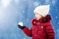 Adorable little girl having fun in beautiful winter park. Cute child playing in a snow. Royalty Free Stock Photo