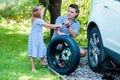 Adorable little girl helping father to change a car wheel outdoors on beautiful summer day Royalty Free Stock Photo