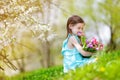 Adorable little girl holding tulips for her mother in blooming cherry garden Royalty Free Stock Photo