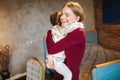 Adorable little girl hug her beautiful and young godmother. Portrait of happy woman hug her goddaughter at home. Cute