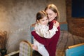 Adorable little girl hug her beautiful and young godmother. Portrait of happy woman hug her goddaughter at home. Cute