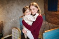 Adorable little girl hug her beautiful and young godmother. Portrait of happy woman hug her goddaughter at home. Cute