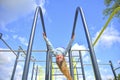 Adorable little girl laughing happily, hanging upside down on parallel bars at playground .