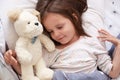 Adorable little girl lay down with closed eyes, child wearing white pajama lying on white cover bed, sleeping in comfortable room Royalty Free Stock Photo