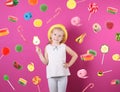 Adorable little girl with lollypop and flying candies on background