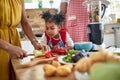 Adorable little girl looking at how her mother is cutting up vegetables, standing in the kicthen with father by her side, making Royalty Free Stock Photo