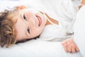 Adorable little girl lying in the bed and smiling in the early morning