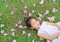 Adorable little girl lying on green grass with fall pink flower in the garden outdoor Royalty Free Stock Photo