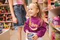 Adorable little girl with mom shopping for toys. Cute female in toy store. Happy young girl selecting toy