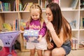 Adorable little girl with mother shopping for toys. Cute female in toy store. Happy young girl selecting toy with her