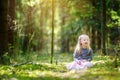 Adorable little girl picking the first flowers of spring in the woods on beautiful sunny spring day Royalty Free Stock Photo