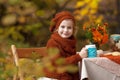 Adorable little girl on picnic in autumn park. Cute little girl having tea party outside in the autumn garden. Girl drinking tea