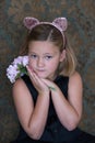 Little girl in pink cat hairband and black sleeveless dress holding a bouquet Royalty Free Stock Photo