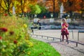 Adorable little girl in pink knitted poncho walking in Luxembourg garden