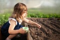 Adorable little girl planting seeds in the ground at the greenhouse