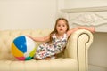 Little girl with a ball on the couch.