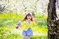 Adorable little girl playing in blooming apple tree garden on Easter egg hunt. Child in spring fruit orchard with cherry blossom Royalty Free Stock Photo