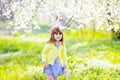 Adorable little girl playing in blooming apple tree garden on Easter egg hunt. Child in spring fruit orchard with cherry blossom