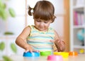 Adorable little girl playing with cup toys, smiling. Royalty Free Stock Photo