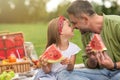 Adorable little girl playing with her loving daddy while eating watermelon, family having a picnic in the green park on Royalty Free Stock Photo