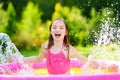 Adorable little girl playing in inflatable baby pool. Happy kid splashing in colorful garden play center on hot summer day. Royalty Free Stock Photo