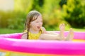 Adorable little girl playing in inflatable baby pool. Happy kid splashing in colorful garden play center on hot summer day. Royalty Free Stock Photo