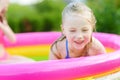 Adorable little girl playing in inflatable baby pool. Happy kid splashing in colorful garden play center on hot summer day. Royalty Free Stock Photo