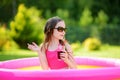 Adorable little girl playing in inflatable baby pool. Happy kid splashing in colorful garden play center on hot summer day. Royalty Free Stock Photo