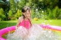 Adorable little girl playing in inflatable baby pool. Happy kid splashing in colorful garden play center on hot summer day. Royalty Free Stock Photo