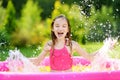 Adorable little girl playing in inflatable baby pool. Happy kid splashing in colorful garden play center on hot summer day. Royalty Free Stock Photo