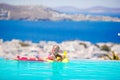 Adorable little girl playing in outdoor swimming pool with beautiful view