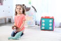 Adorable little girl playing with soft toys on carpet at home Royalty Free Stock Photo