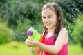 Adorable little girl playing with water gun on hot summer day. Cute child having fun with water outdoors. Royalty Free Stock Photo