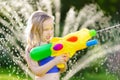 Adorable little girl playing with water gun on hot summer day. Cute child having fun with water outdoors. Royalty Free Stock Photo