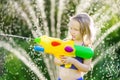 Adorable little girl playing with water gun on hot summer day. Cute child having fun with water outdoors. Royalty Free Stock Photo