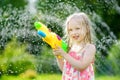 Adorable little girl playing with water gun on hot summer day. Cute child having fun with water outdoors. Royalty Free Stock Photo