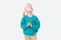 Adorable little girl praying and looking up while standing against white background Royalty Free Stock Photo