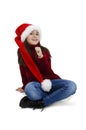 Adorable little girl in red Santa hat sitting on floor, looking up. Christmas little girl. Royalty Free Stock Photo